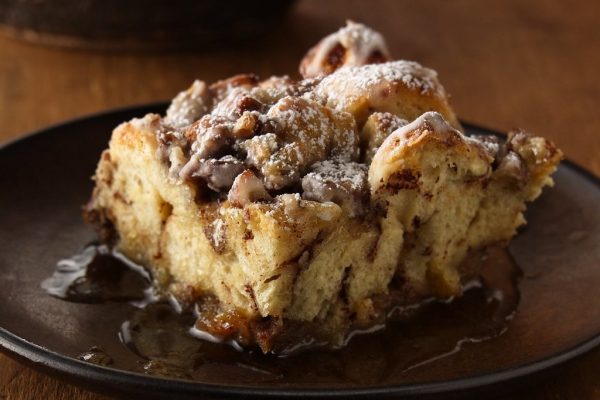 French Toast Casserole: A golden-brown baked dish with layers of fluffy bread cubes soaked in a rich custard, topped with a buttery streusel and dusted with powdered sugar, served with fresh berries and maple syrup.